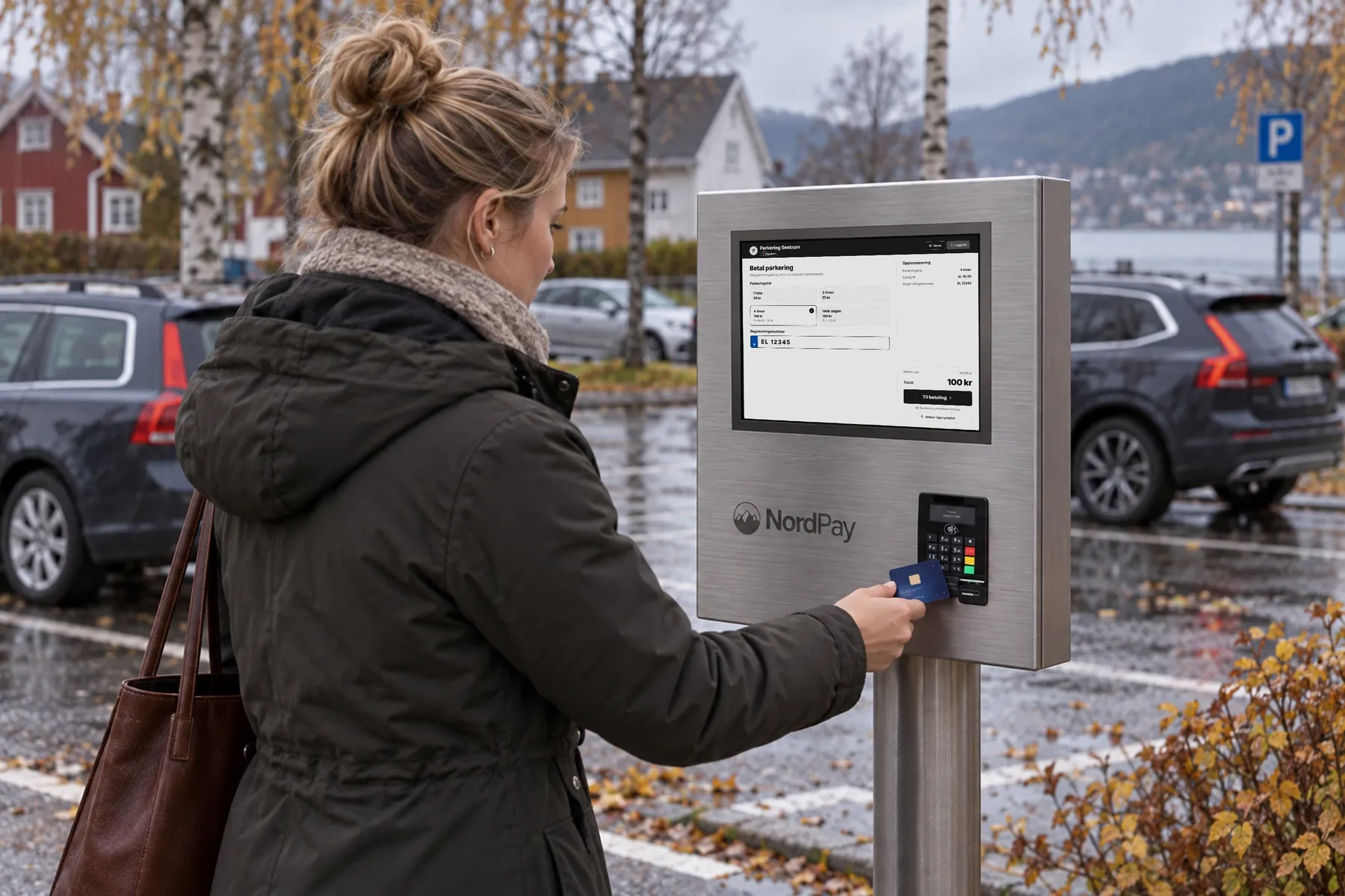 Kvinne betaler med bankkort på en betalingsautomat på stolpe ved en utendørs parkeringsplass